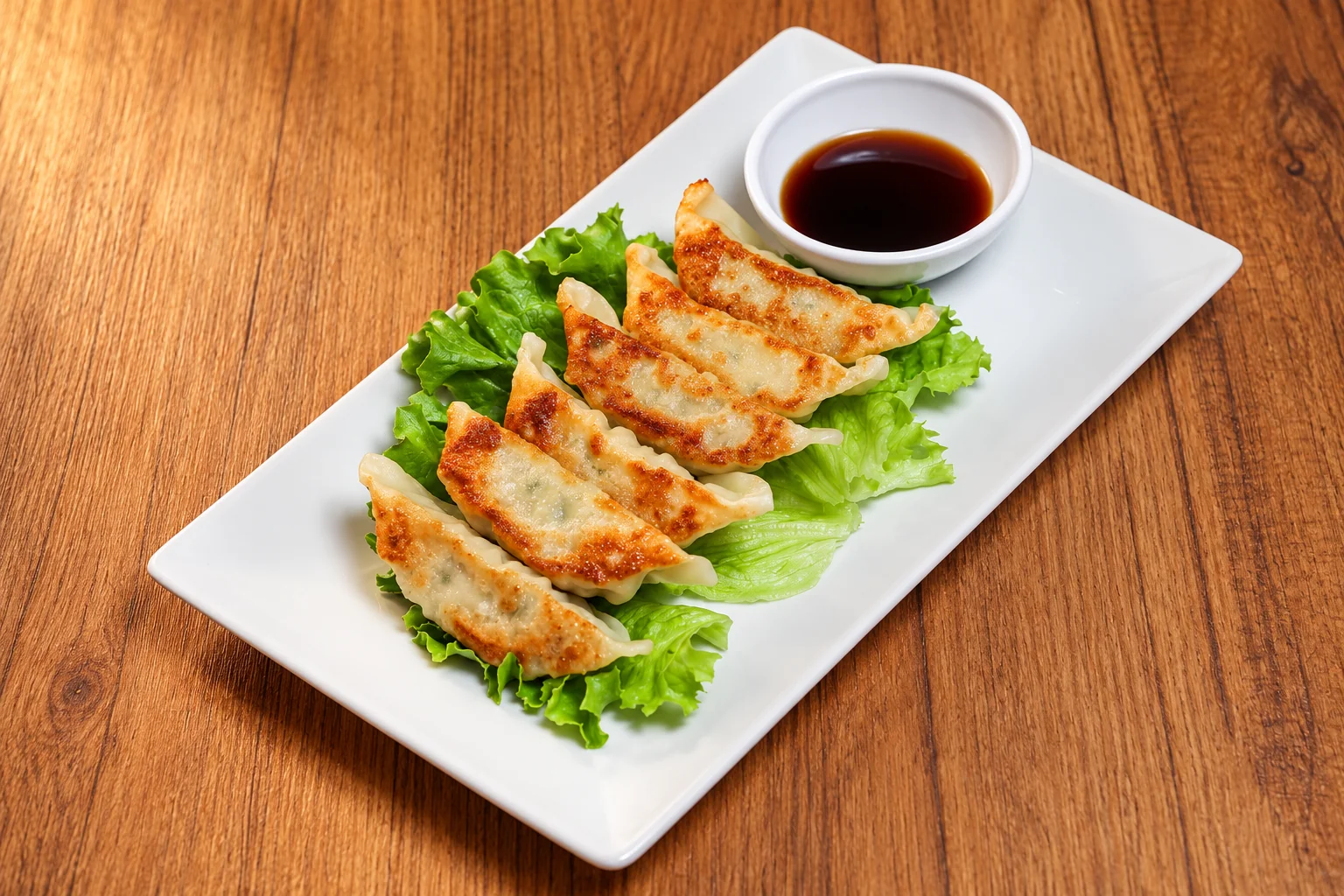Grilled chicken dumplings on lettuce, white rectangular plate, wooden table