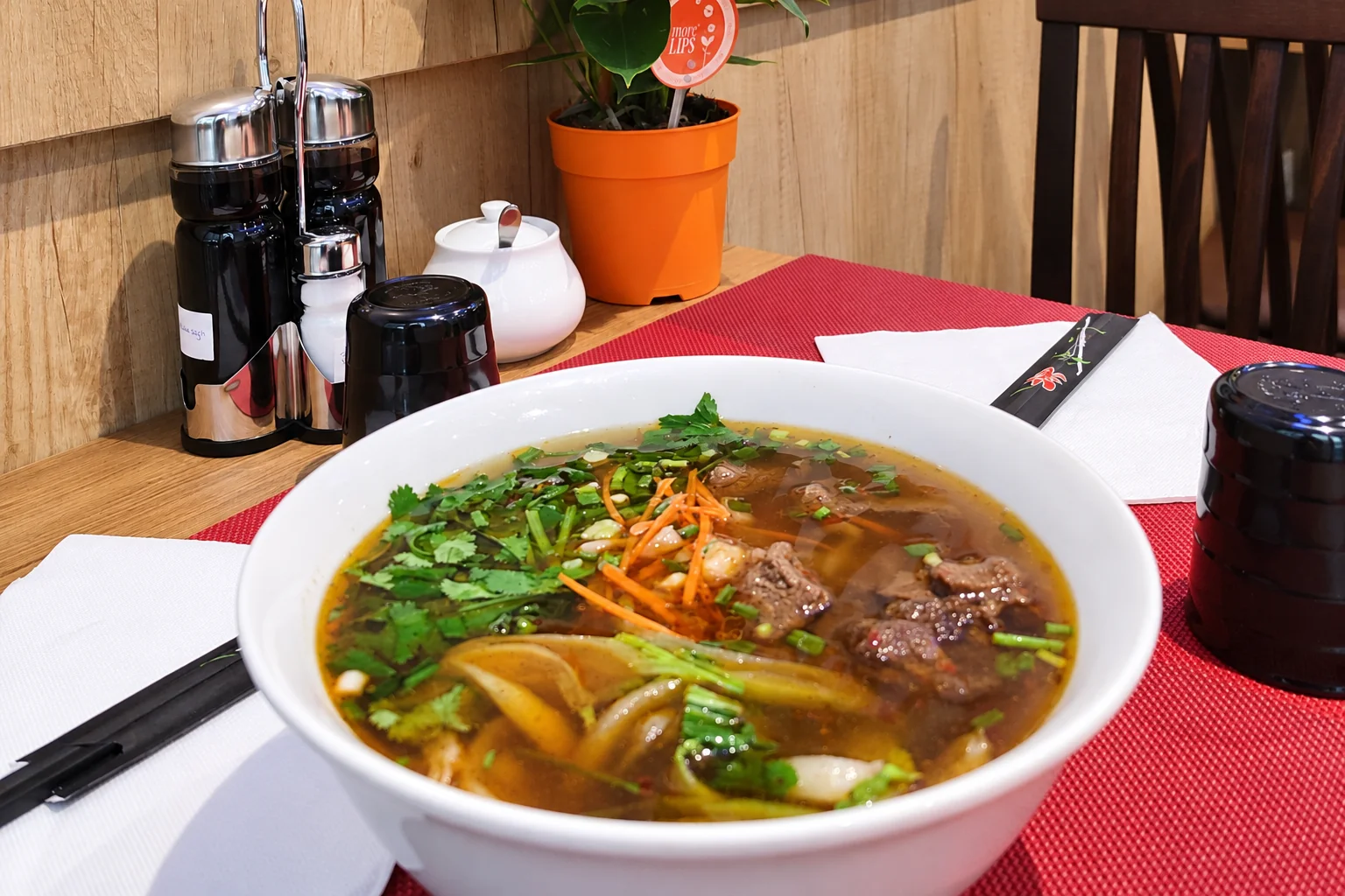 Noodle soup in a white bowl, red placemat